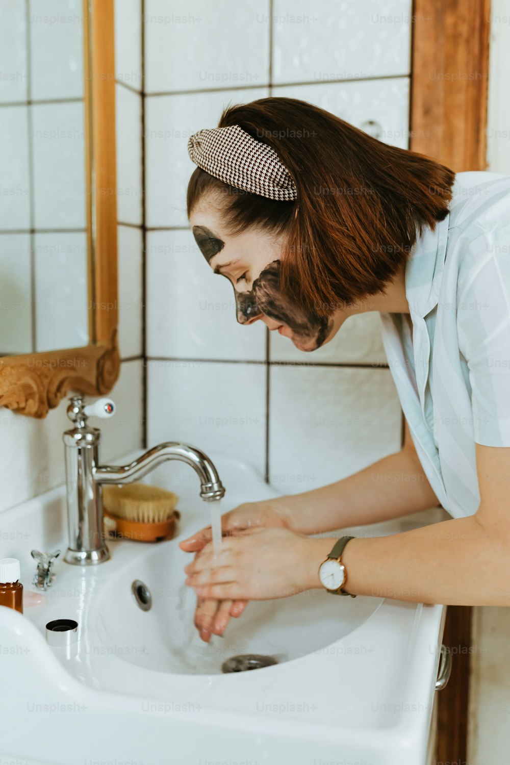 a woman washing her hands in a bathroom sink