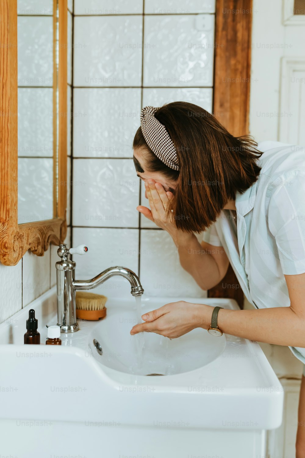 a woman is cleaning her face in the bathroom
