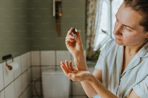 Una donna in camicia bianca tiene in mano un piccolo oggetto