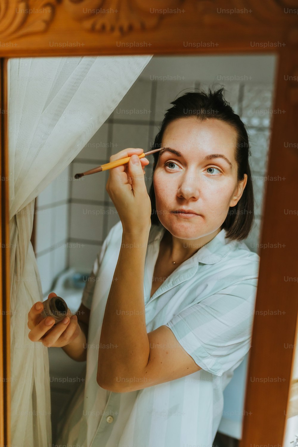 a woman in a white shirt is brushing her teeth
