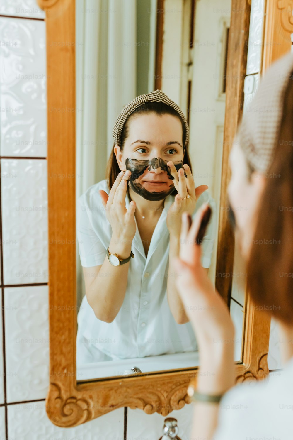 a woman is shaving her face in front of a mirror