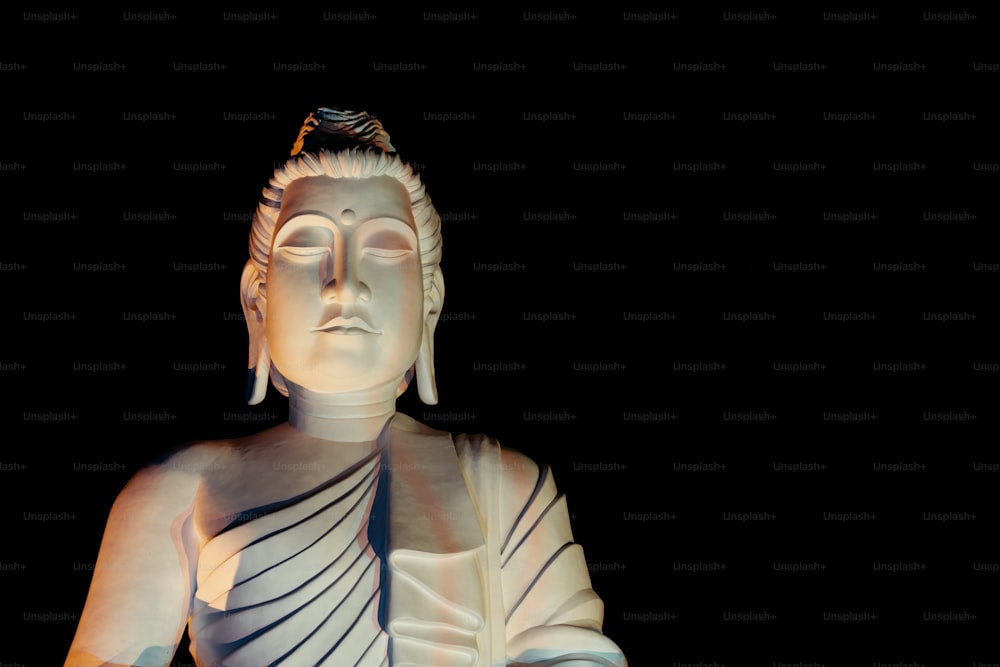 uma estátua branca de Buda sentada no escuro