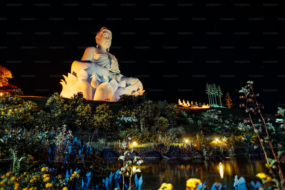 a large buddha statue sitting on top of a lush green hillside