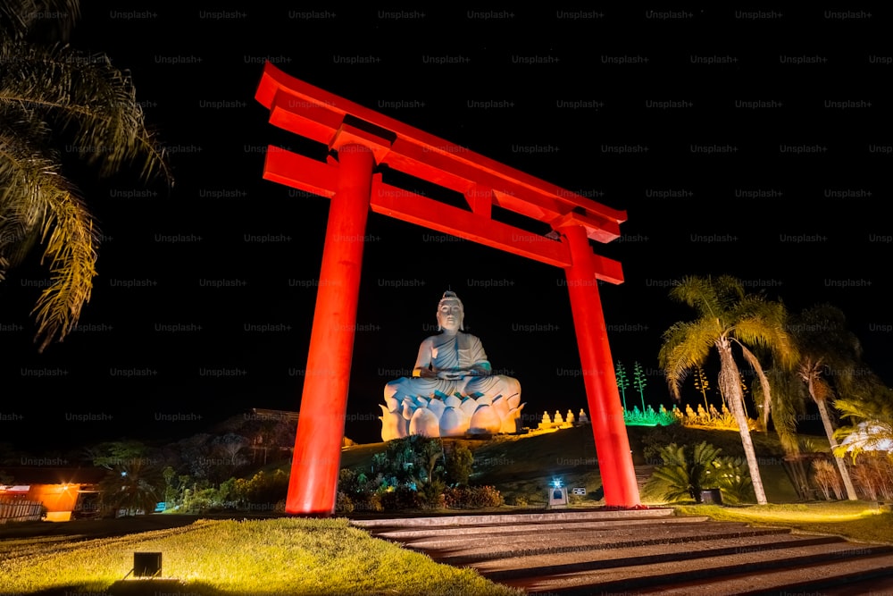 a statue of a buddha sitting on top of a red gate