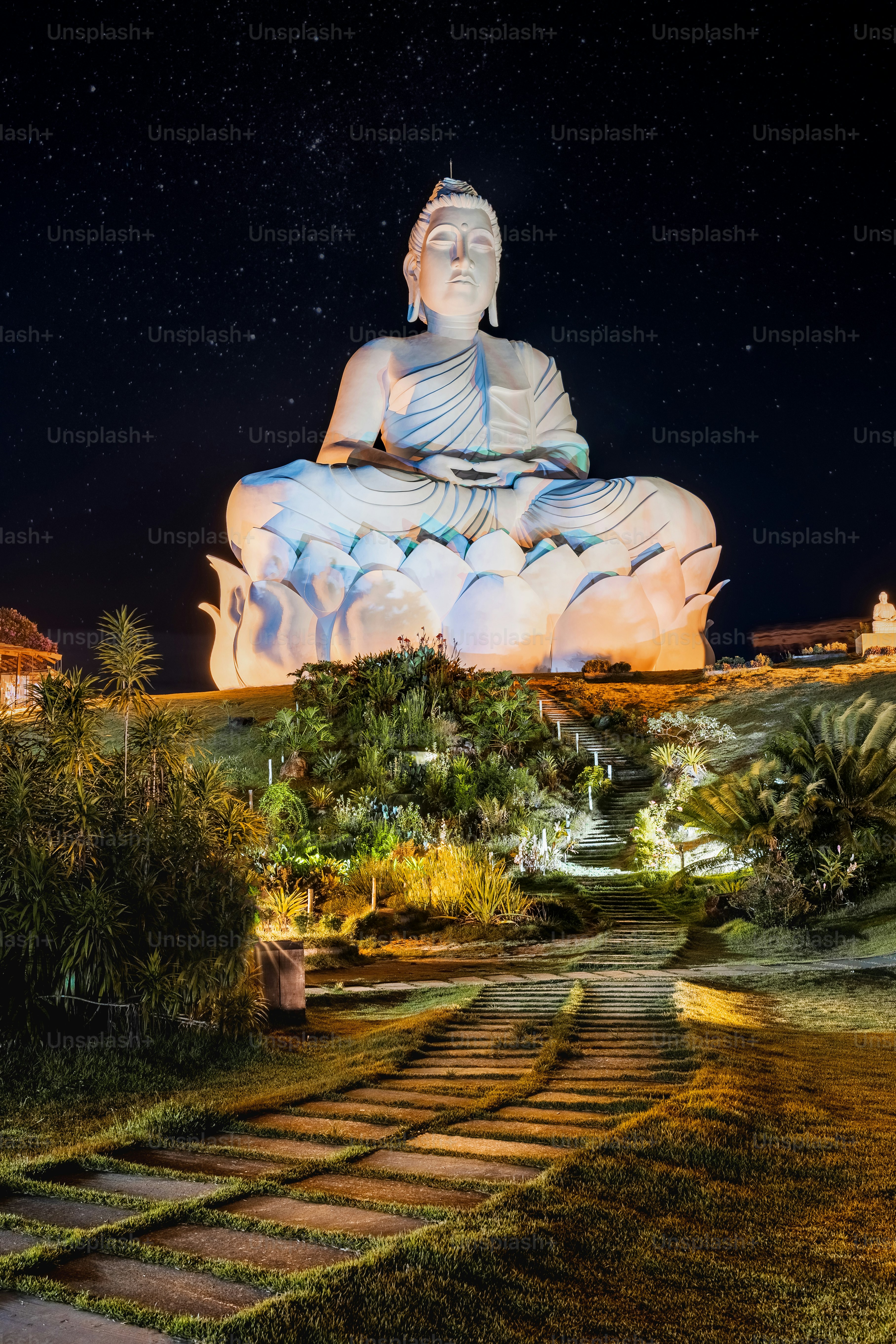 a large buddha statue sitting on top of a lush green field