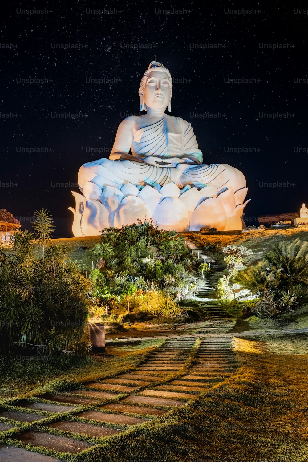 a large buddha statue sitting on top of a lush green field