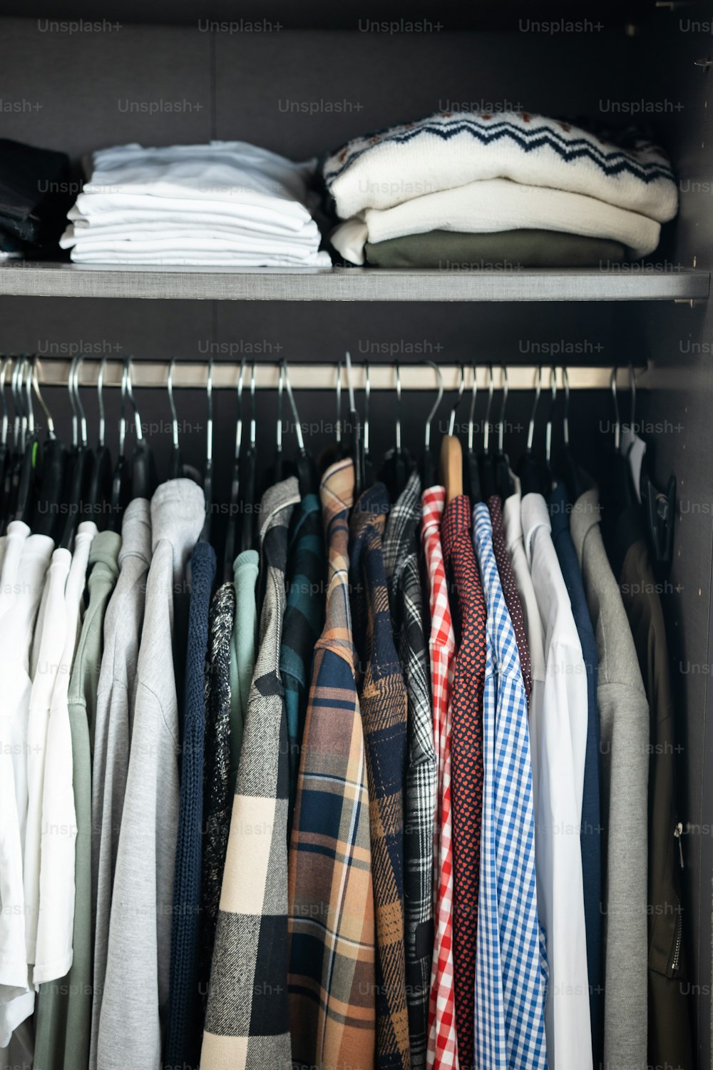 Un montón de camisas están colgadas en un estante