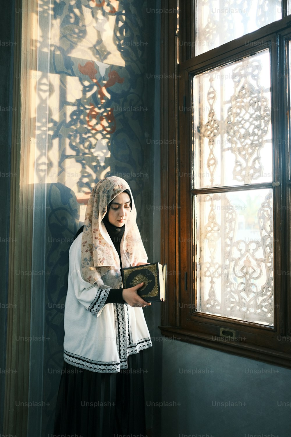 Eine Frau in einem weiß-schwarzen Outfit, die ein Buch hält