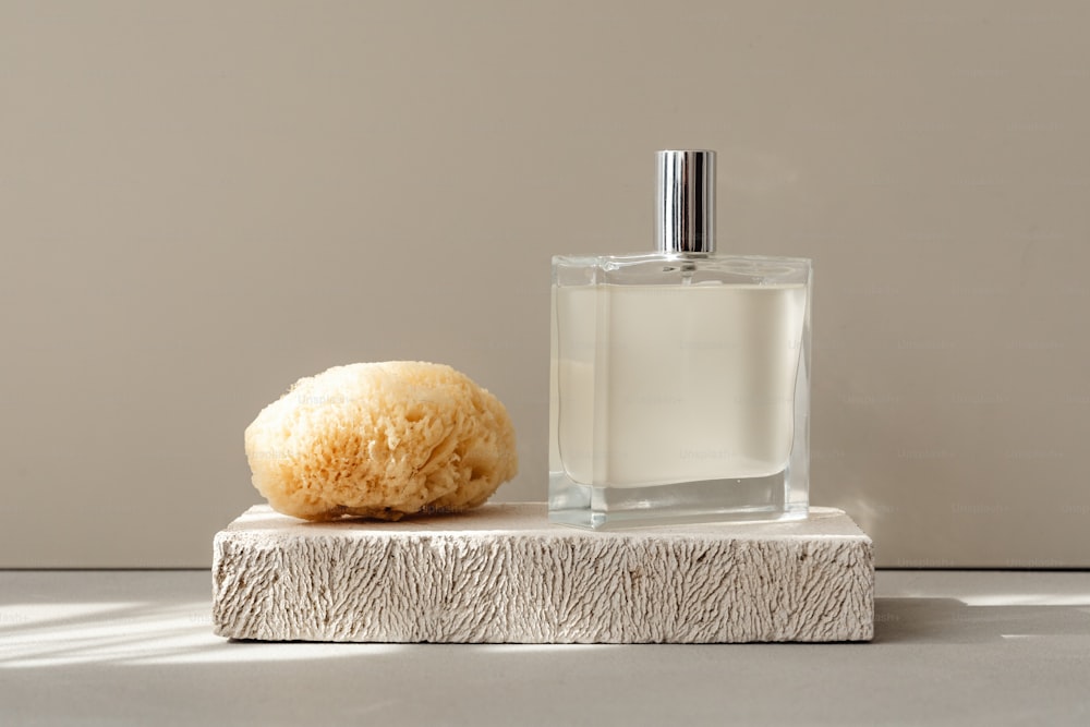 a bottle of cologne next to a sponge on a table