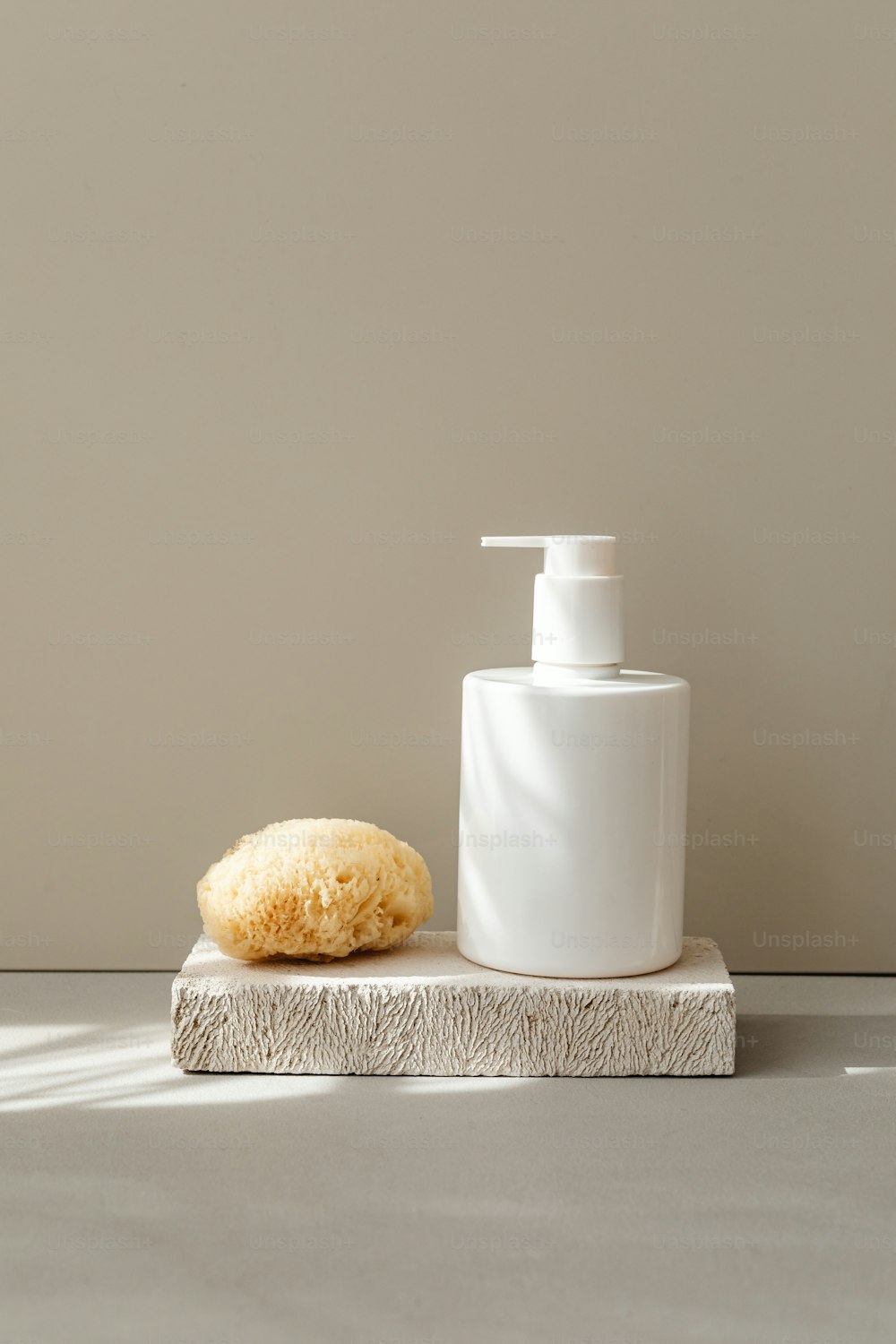 un dispensador de jabón y una esponja en una losa de piedra