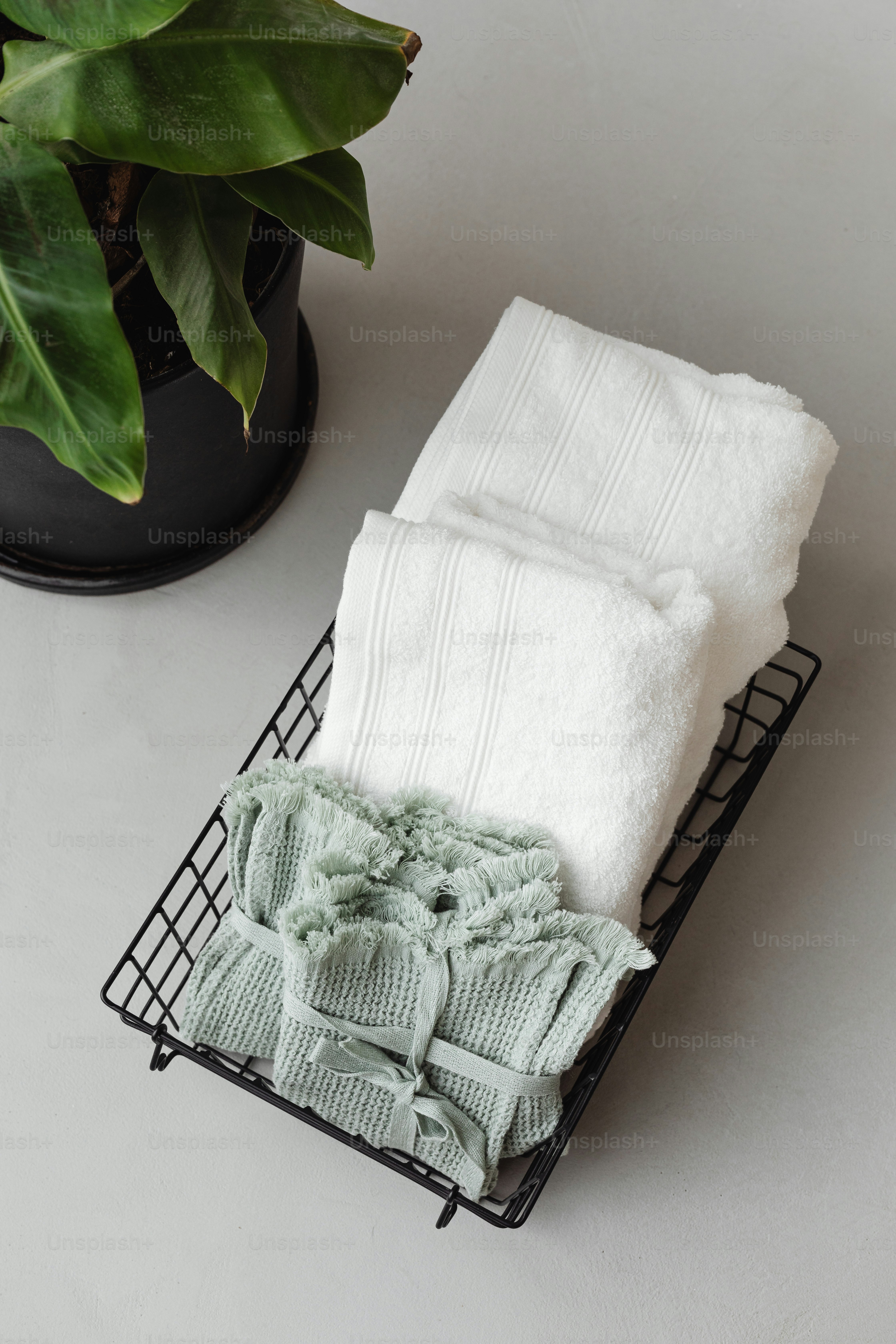 un panier de serviettes pliées à côté d’une plante en pot