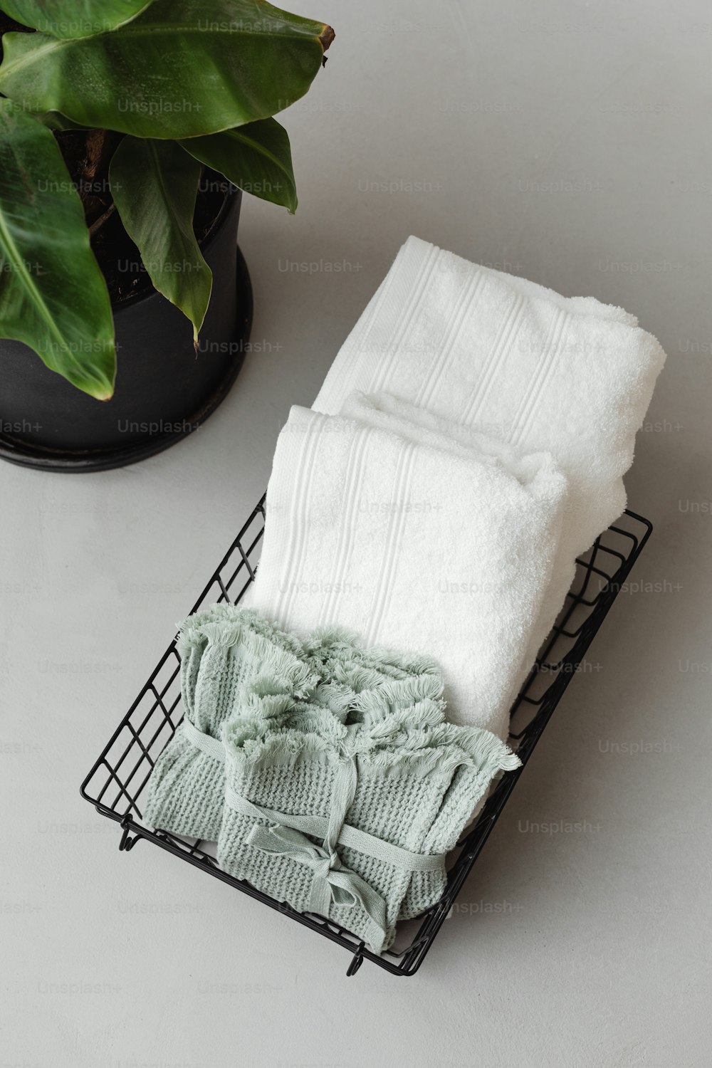 a basket of folded towels next to a potted plant