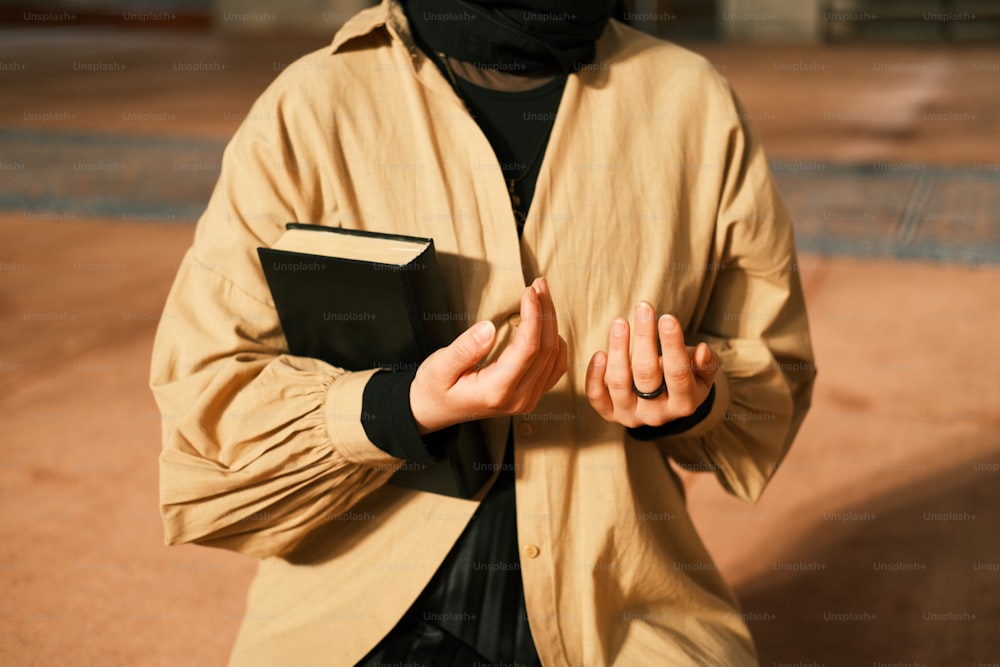 a man wearing a burka holding a book in his hands