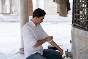 um homem sentado no chão consertando uma torneira