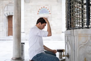 a man sitting on the ground with his head in his hands