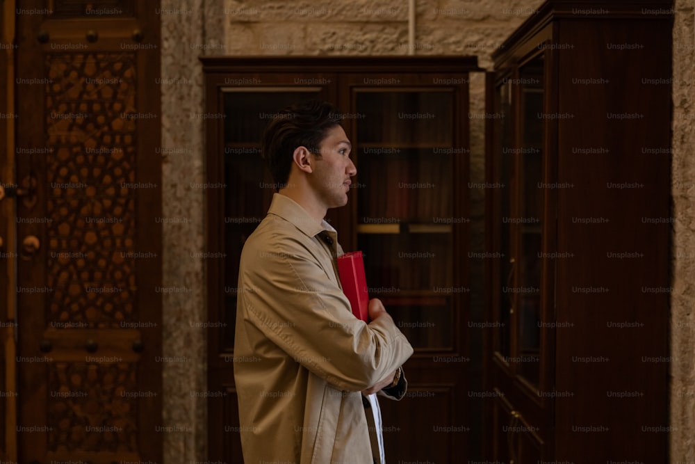 a man in a trench coat holding a red umbrella