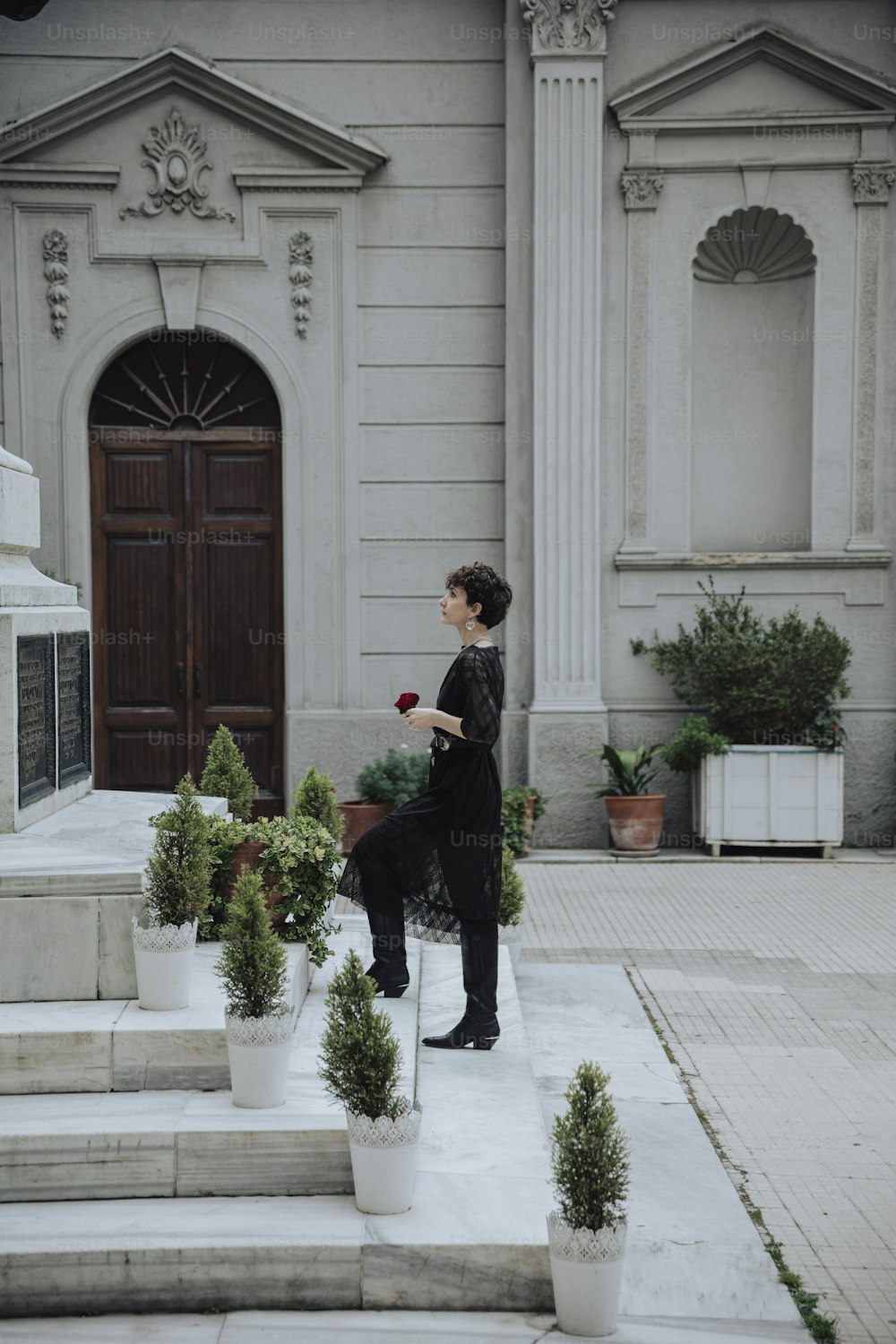 Une femme en robe noire debout devant un immeuble