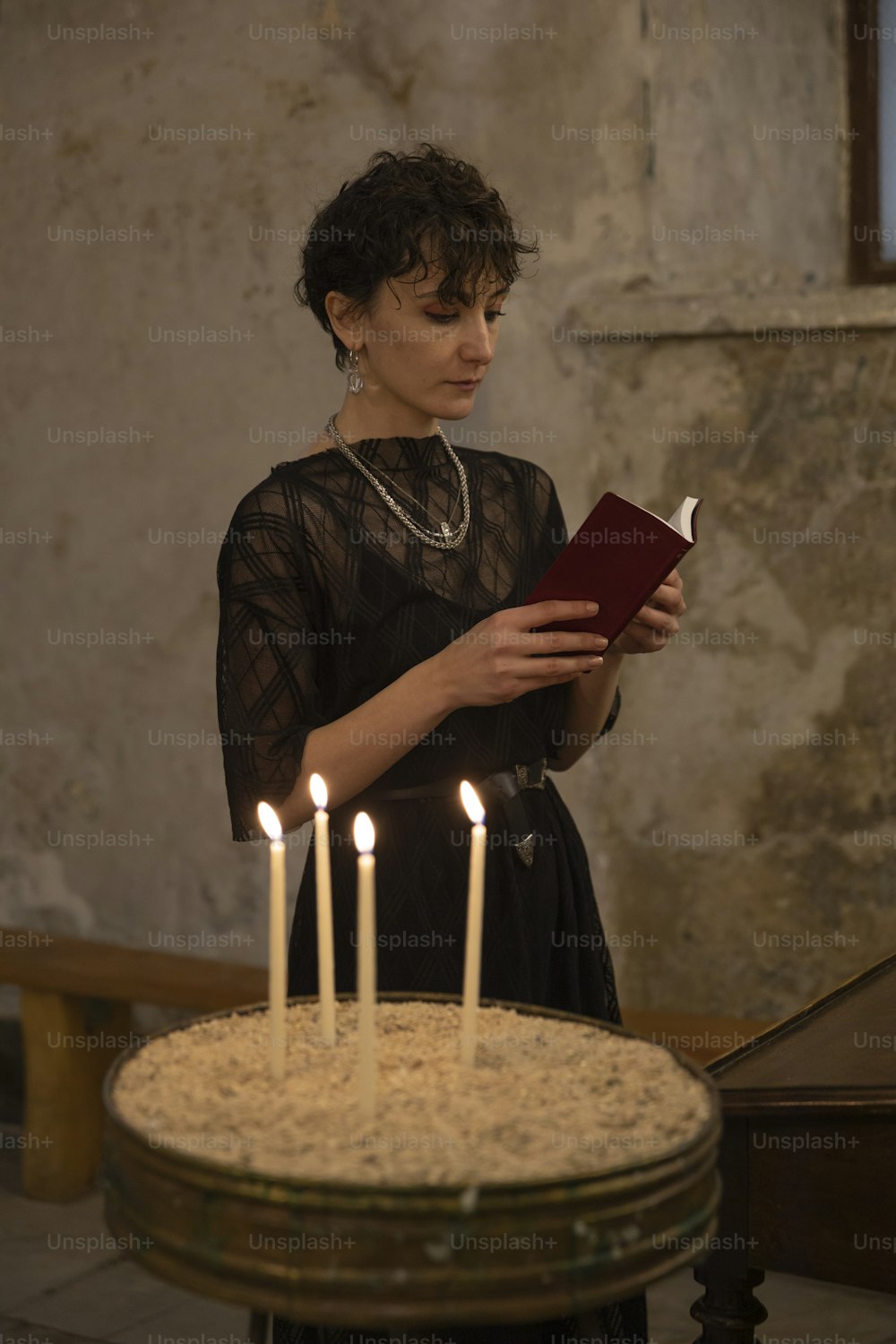 uma mulher em pé na frente de um bolo com velas