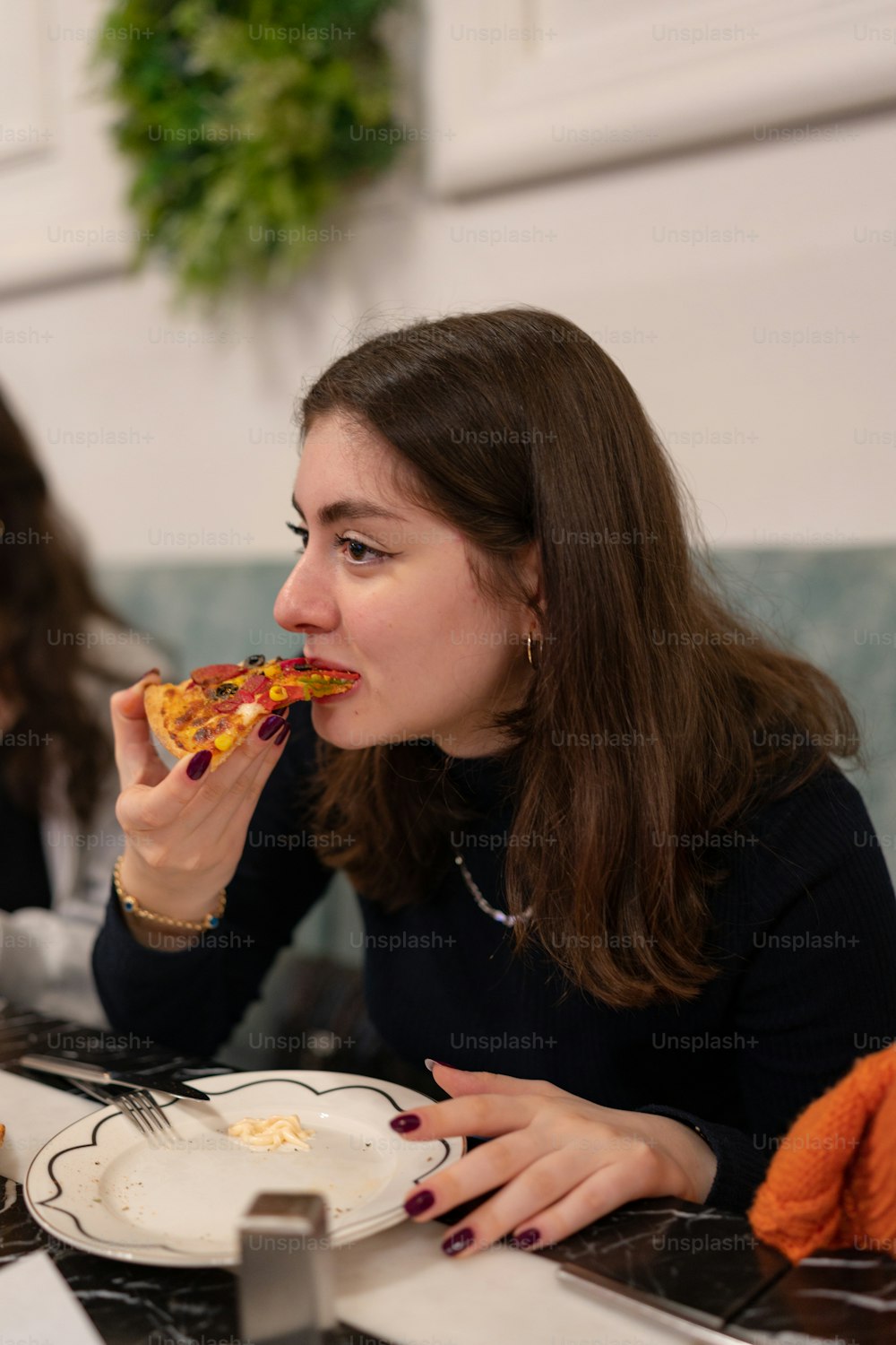 una donna seduta a un tavolo che mangia una fetta di pizza