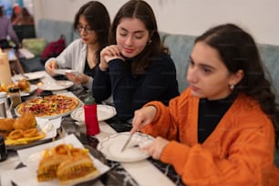 음식 접시가 있는 테이블에 앉아 있는 한 무리의 여성들
