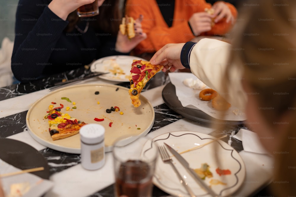 テーブルの周りに座ってピザを食べる人々のグループ