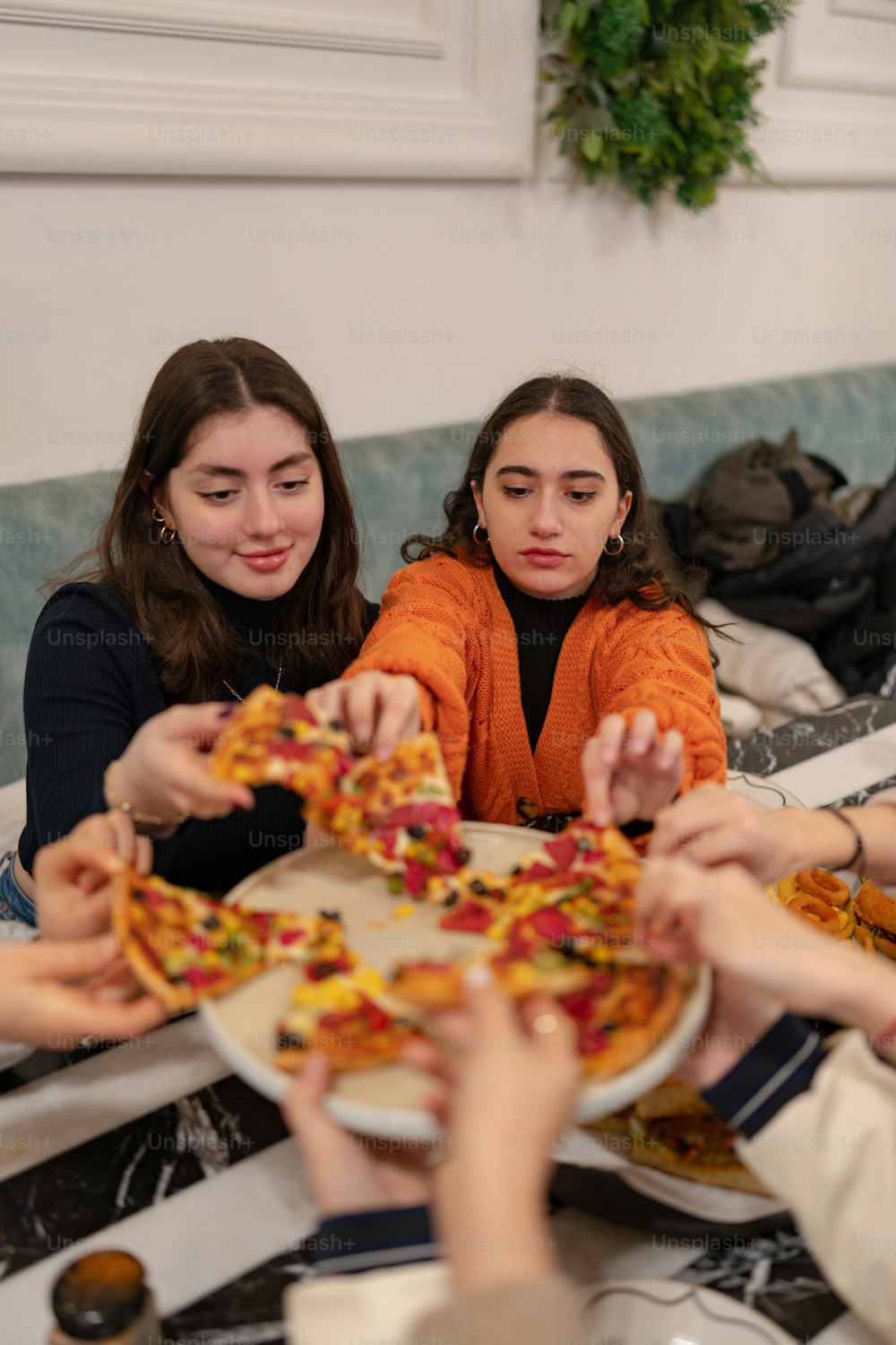 a group of women sitting around a table eating pizza