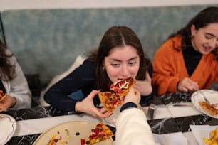 a group of women sitting at a table eating pizza