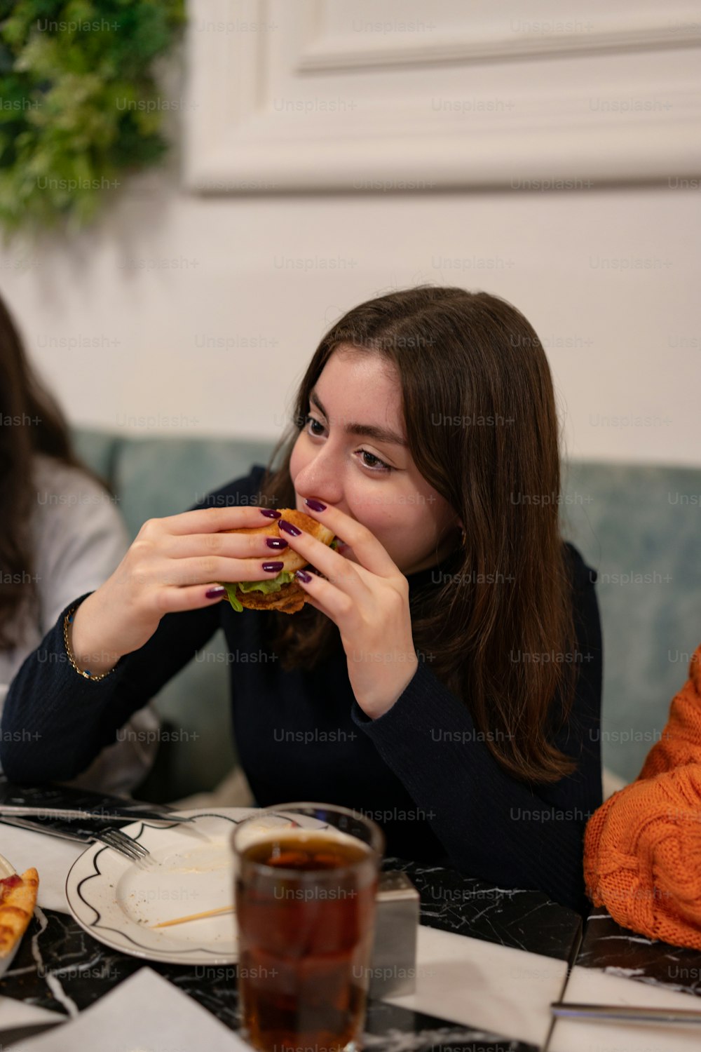 a woman sitting at a table eating a sandwich