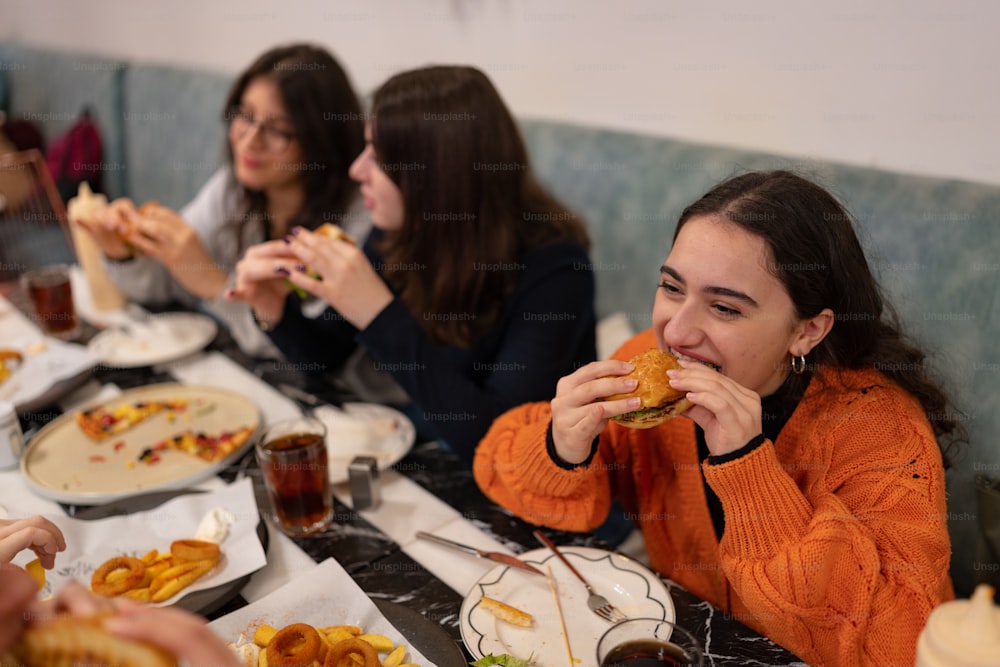 Un grupo de mujeres sentadas en una mesa comiendo alimentos