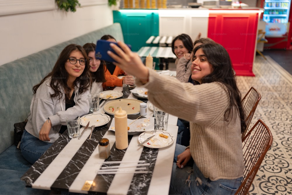 a group of women sitting at a table taking a picture