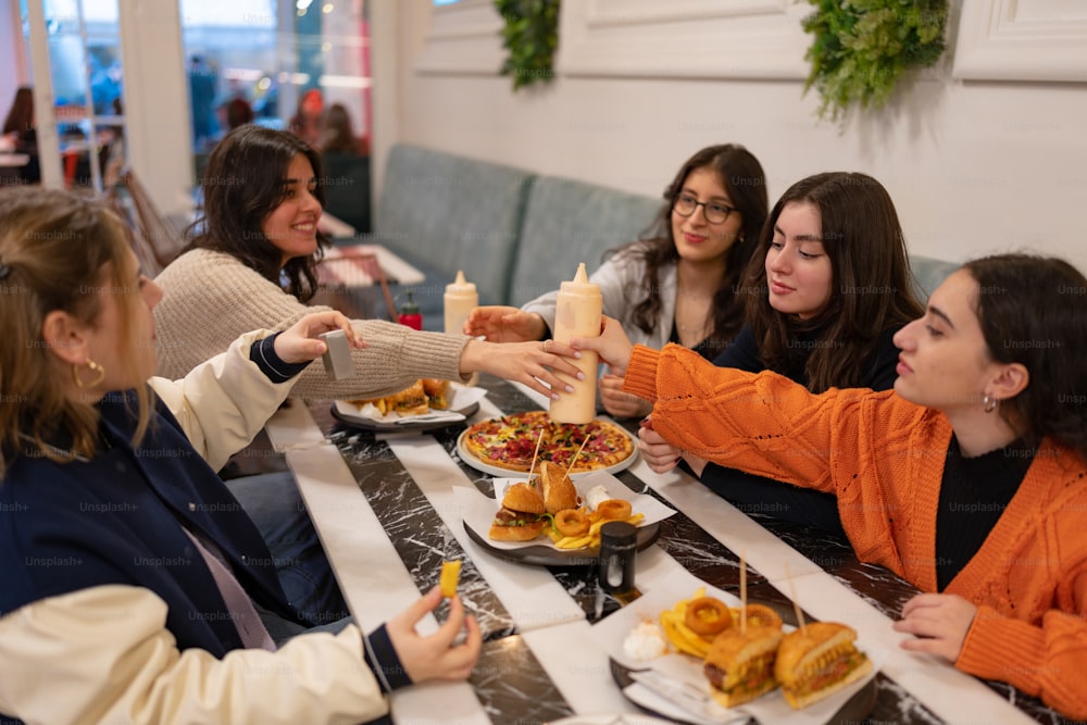 Un grupo de mujeres sentadas en una mesa con platos de comida