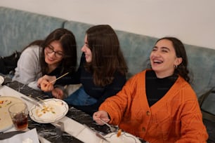 テーブルに座って食べ物を食べる女性のグループ
