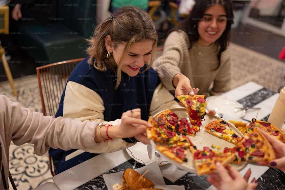 a group of women sitting around a table eating pizza