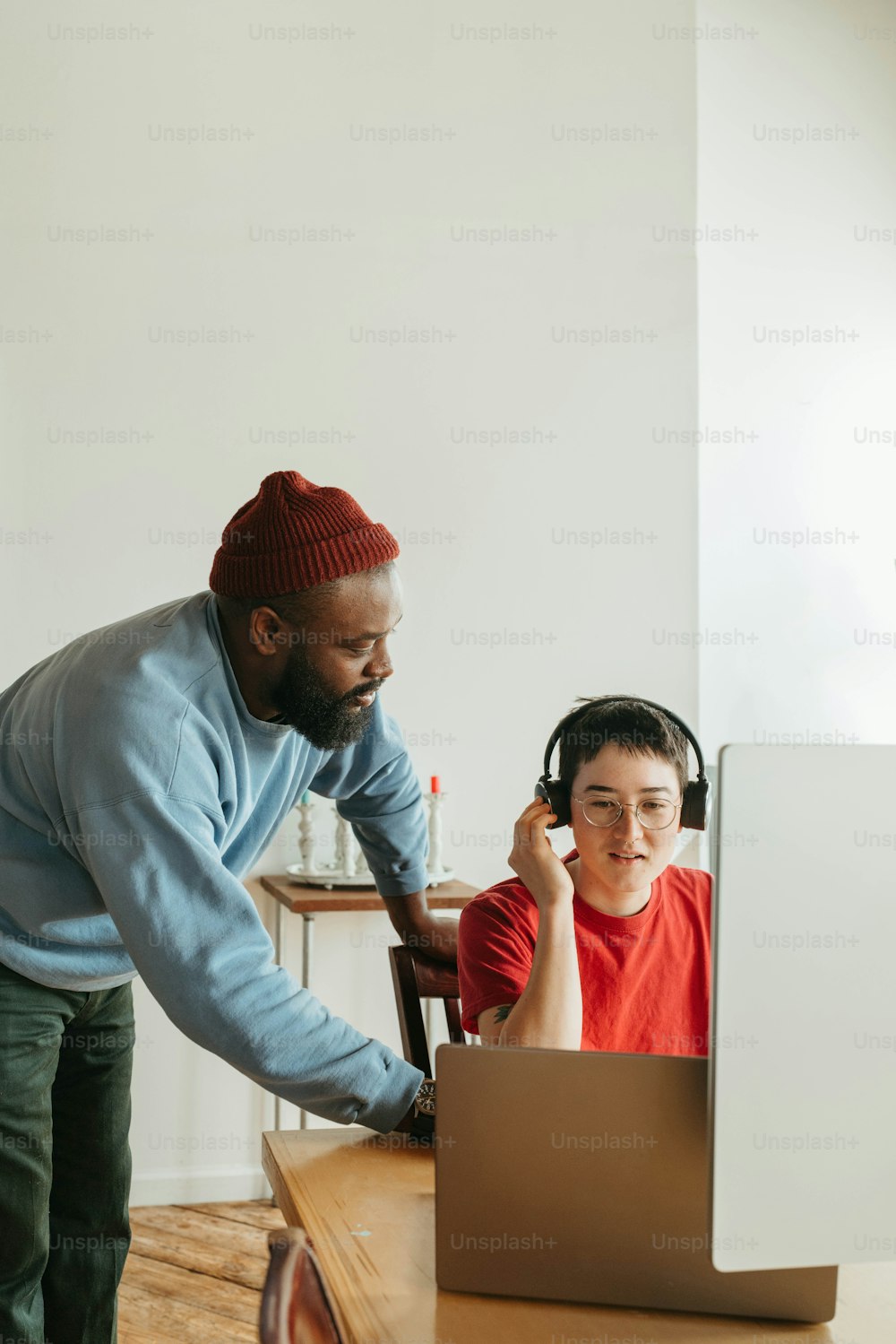 a man standing next to a boy on a laptop computer