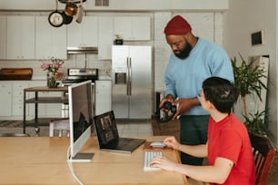 a man and a boy sitting at a table with a laptop