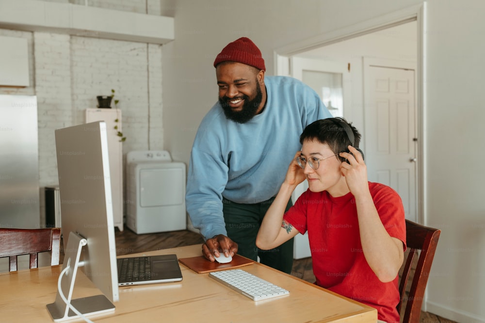 a man standing next to a woman at a computer