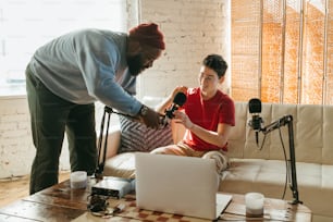 a man sitting on a couch next to a woman holding a microphone