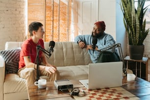 a man sitting on a couch next to a woman on a laptop