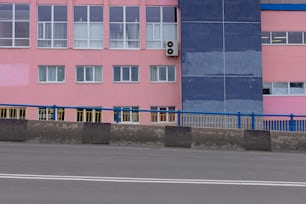 a blue and pink building next to a street