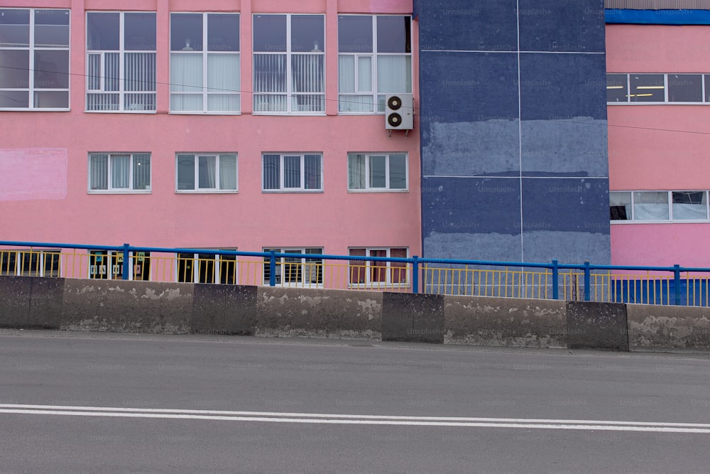 a blue and pink building next to a street