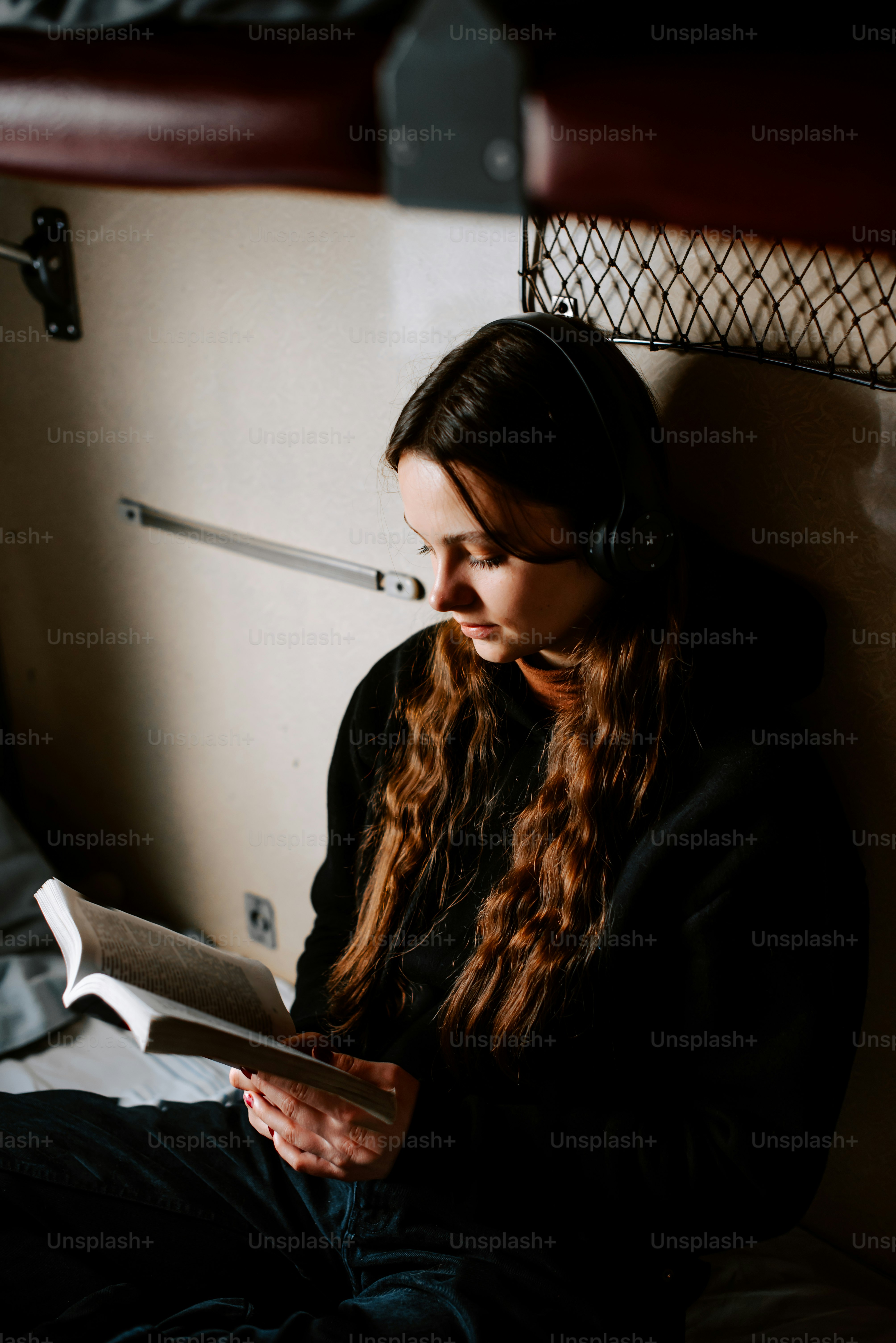 une femme assise sur un lit en train de lire un livre
