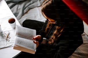 a woman sitting on a bed reading a book