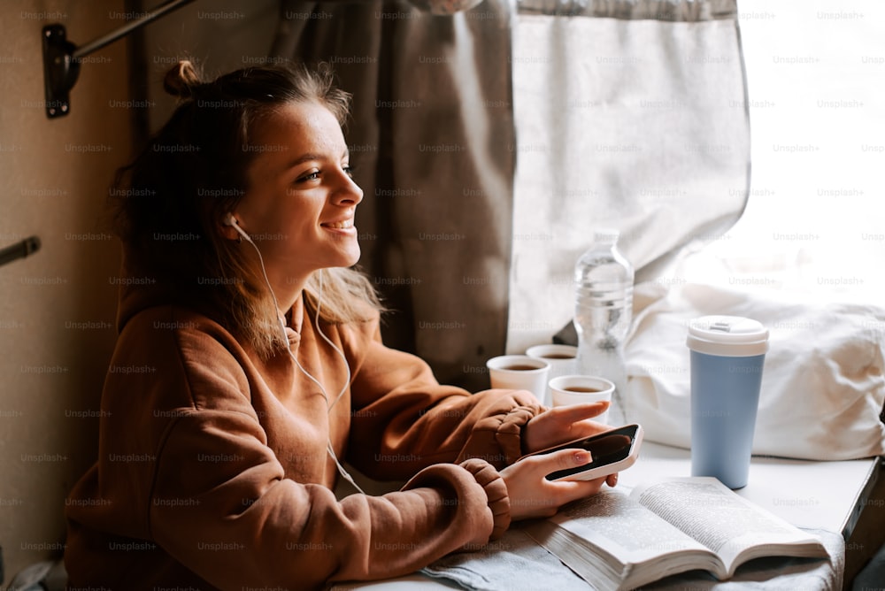 Eine Frau sitzt an einem Tisch mit einem Buch und einer Tasse Kaffee