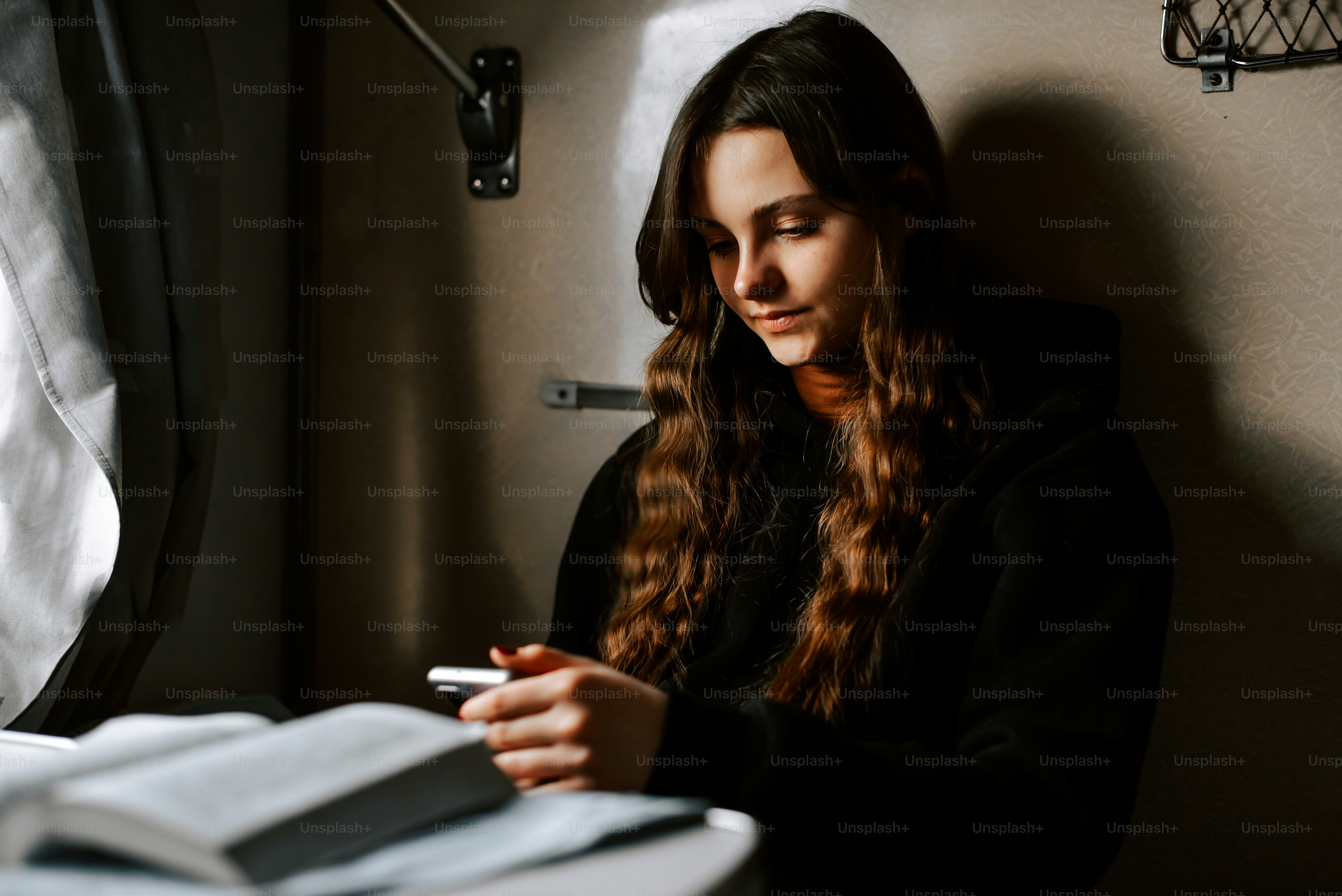 une femme assise devant une fenêtre en train de lire un livre