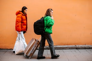 two women walking down the street with their luggage