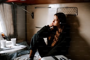 a woman sitting on a bed with headphones on