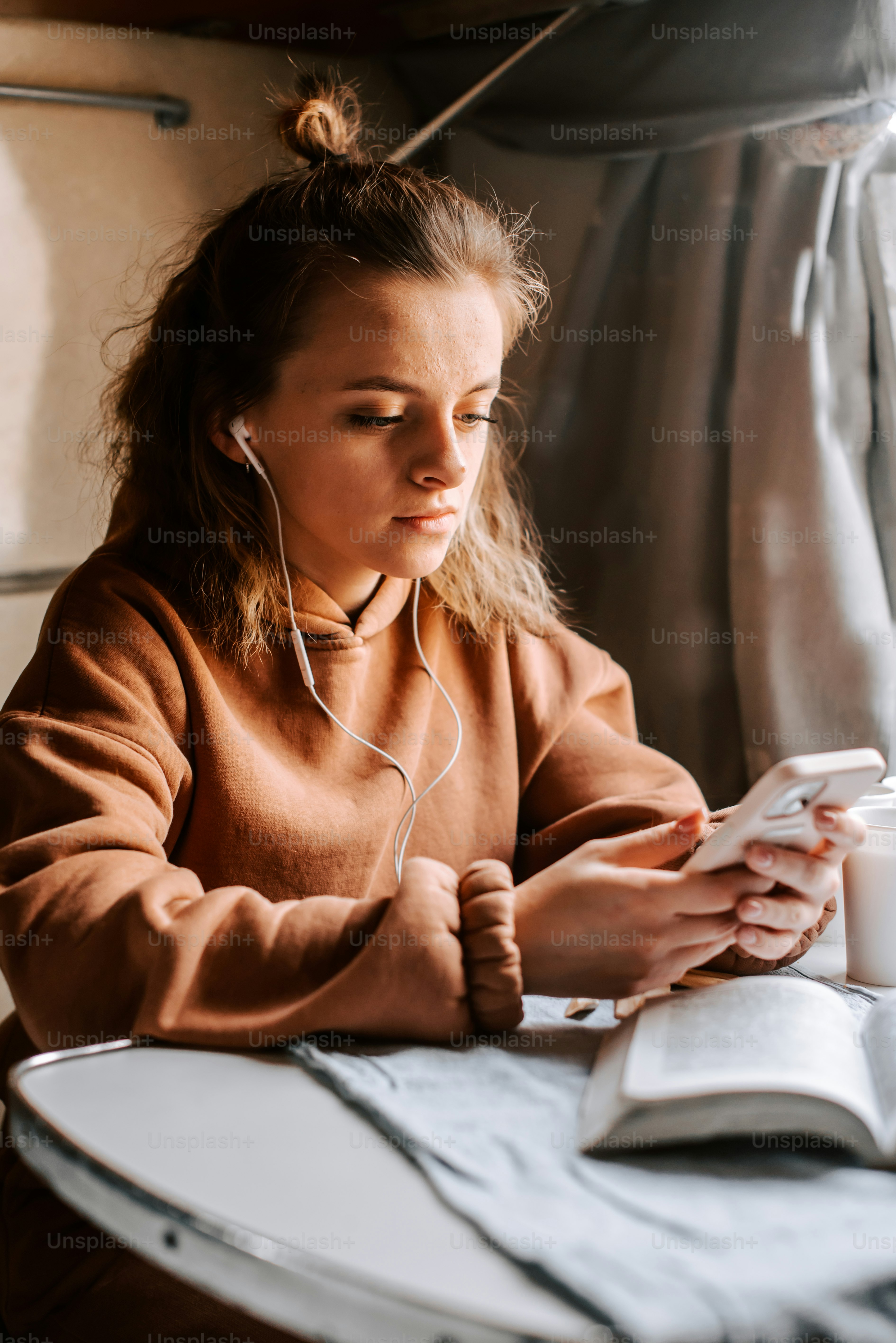 Una mujer sentada en una mesa con un libro y auriculares