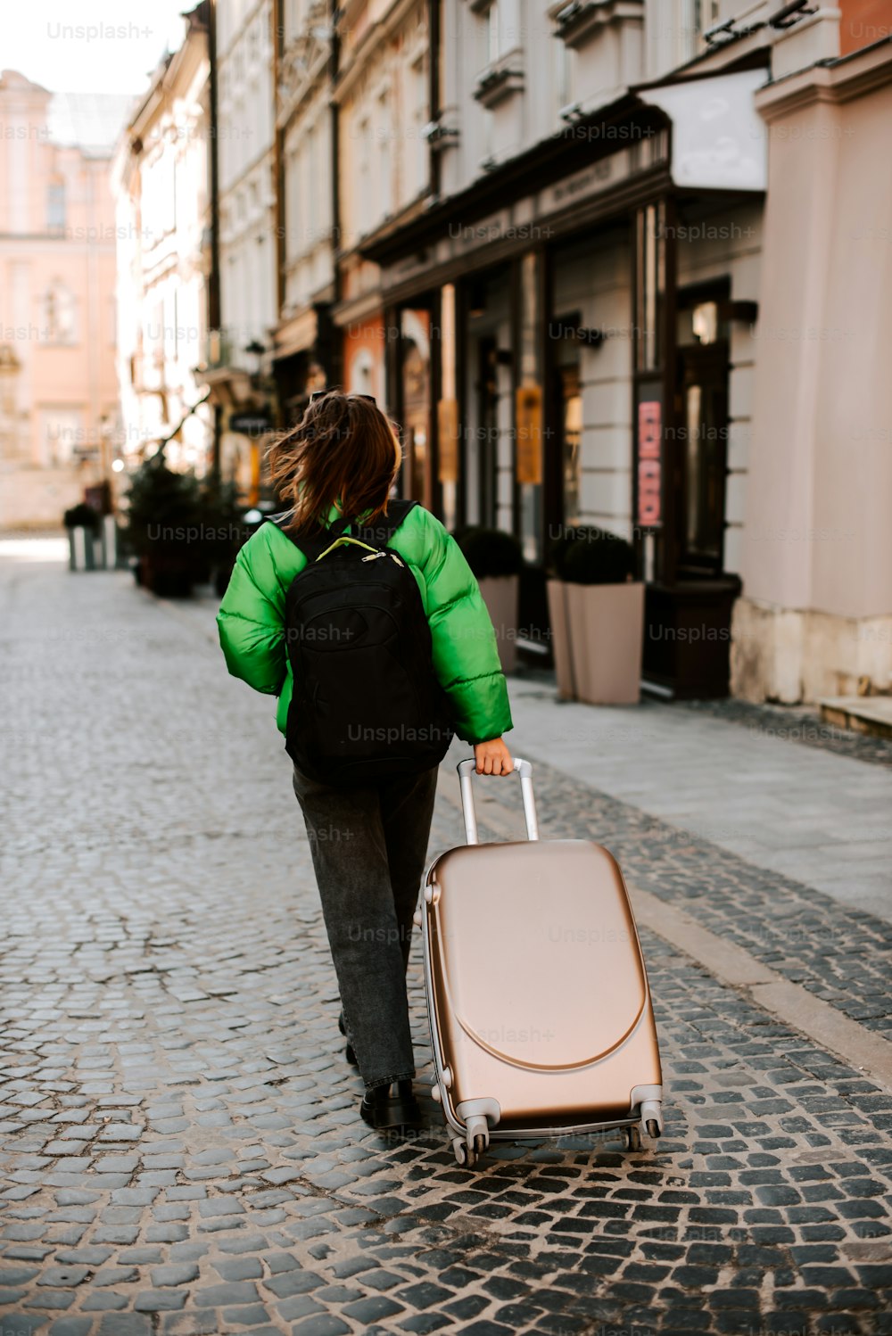 a woman walking down a street with a suitcase