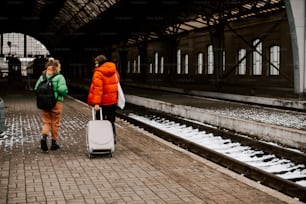 two people with luggage walking down a train platform