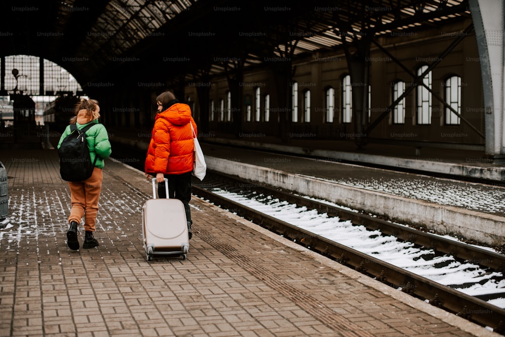 two people with luggage walking down a train platform